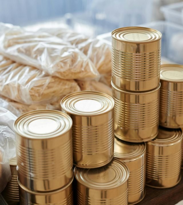 A stack of canned goods and packaged foods on a table, perfect for donation drives.